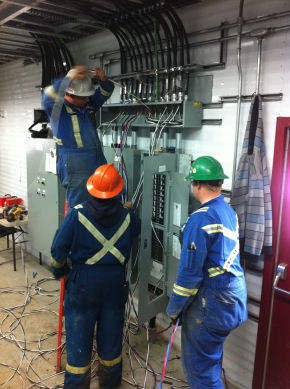 Two electrician apprentices helping the journeyman electrician